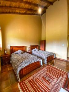 a bedroom with two beds and a rug at B&B Cotacachi Hosteria Oro Azul in Cotacachi