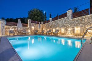 a swimming pool with chairs and a stone wall at Villa Amantia in Chaliotata