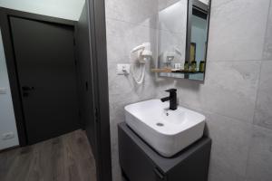 a bathroom with a white sink and a mirror at NORTH GATE Rooms in Afumaţi
