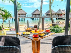 a table with food on it with the ocean in the background at Manava Beach Resort & Spa Moorea in Maharepa