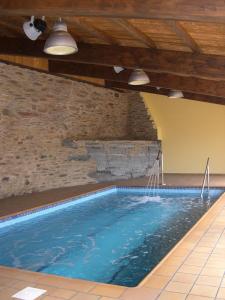a swimming pool in a building with a stone wall at Casa Grande da Ferreria de Rugando in Rugando