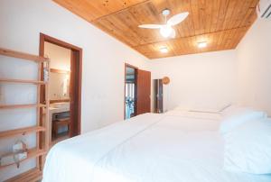 a bedroom with a white bed with a wooden ceiling at Casa Orybá in Prado +20 photos