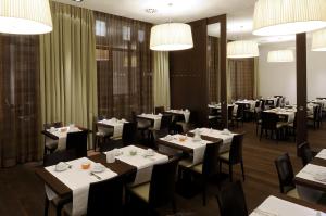 a restaurant with white tables and chairs and chandeliers at Hotel Thalmair in Munich