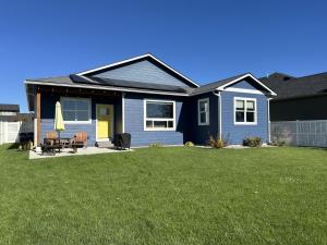 a blue house with a yellow door and a yard at Hometown Place in Missoula