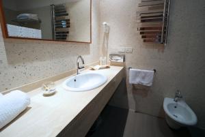 a bathroom with a sink and a mirror and a toilet at Hotel San Rocco in Muggia