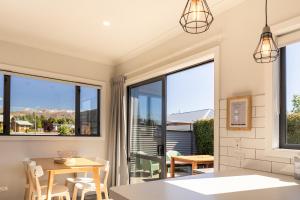a dining room with large windows and a table and chairs at Twizel Cottages in Twizel
