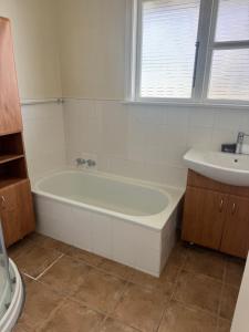 a white bathroom with a tub and a sink at Bristol Motel - HOUSE in Upper Hutt