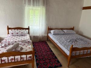 two twin beds in a room with a window at Kulla e Vjetër ,Vermosh in Vermosh