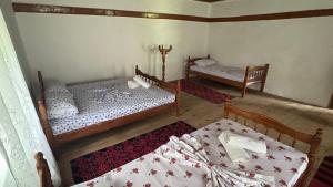a room with two beds and a bed and a table at Kulla e Vjetër ,Vermosh in Vermosh