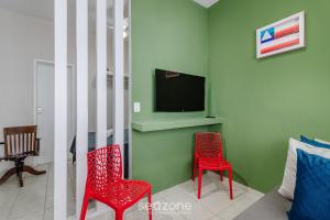a living room with two red chairs and a tv at Studio the city center 300m Pelourinho HAI0203 in Salvador +3 photos