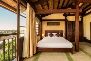 a bedroom with a bed and a large window at Sola Hoi An in Thanh Ðông (1)
