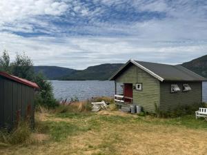 a green house with a bench next to a lake at Longerak Camping in Bygland