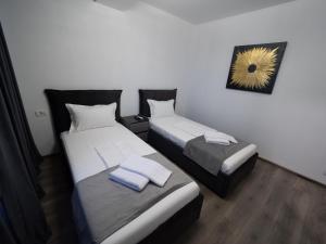 two beds in a small room with towels on them at NORTH GATE Rooms in Afumaţi +4 photos