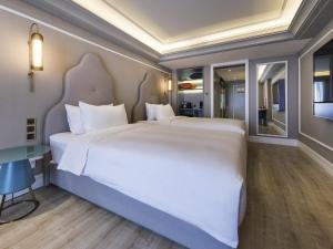 a bedroom with a large white bed and a desk at Mercure Xi'an Downtown in Xi'an