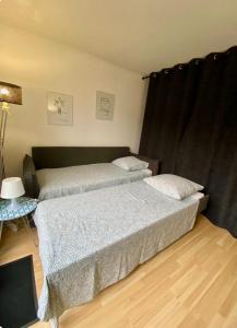 a bedroom with two beds and a table with a lamp at Independent studio - Cicé Blossac Golf in Bruz
