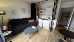 a living room with a couch and a table and a kitchen at Independent studio - Cicé Blossac Golf in Bruz