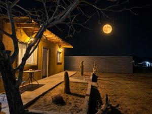a person standing outside a house at night with a full moon at Cabaña Los Cardones in Campanas +8 photos