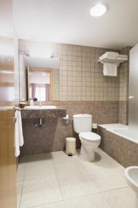 a bathroom with a toilet and a sink and a tub at Hotel Alta Garrotxa in Tortellá