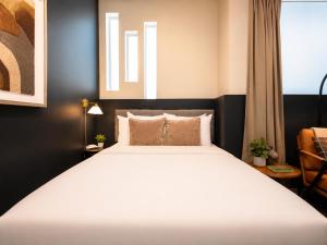 a bedroom with a large white bed in a room at Roami at Zuni in Denver +18 photos