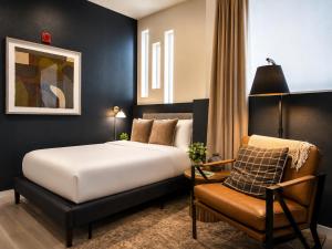 a bedroom with a bed and a chair at Roami at Zuni in Denver