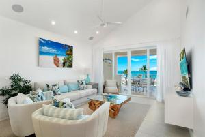 a living room with white furniture and a view of the ocean at Grace Bay Beach Front Penthouse in Long Bay Hills