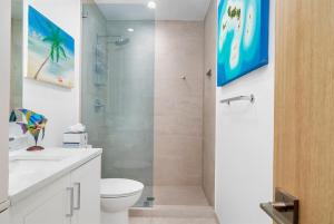 a bathroom with a shower and a toilet and a sink at Grace Bay Beach Front Penthouse in Long Bay Hills +12 photos