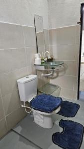a bathroom with a toilet with a mirror and blue mats at Casa Vigia 2 Quartos in Vigia