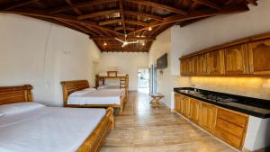 a bedroom with two beds and a kitchen with wooden cabinets at Finca Hotel Monte Carlos in Santa Bárbara