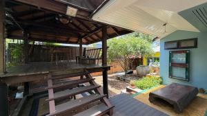 a patio with a wooden deck with a table and a bench at Cozy two-storey home in Ban Lam Praya Phai Rua