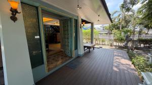 an open door to a porch with a bench on a deck at Cozy two-storey home in Ban Lam Praya Phai Rua