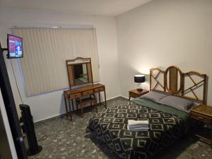 a bedroom with a bed and a mirror and a television at Hostel Paricutín in Uruapan del Progreso