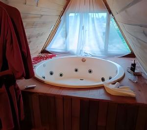 a bath tub sitting on a table next to a window at Imperatriz Cabanas (Chalé 1 com hidromassagem) in Santo Amaro da Imperatriz +63 photos
