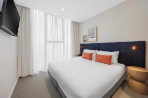 a bedroom with a large white bed with orange pillows at Quest Southport in Gold Coast +14 photos