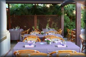 a dining room with tables and chairs and palm trees at Lantana Resort Hotel&Apartments in Pula
