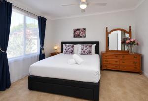 a bedroom with a bed with a mirror and a dresser at Morpeth Cottage in Morpeth