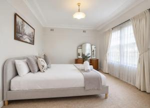 a white bedroom with a bed and a large window at Morpeth Cottage in Morpeth