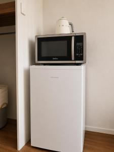 a microwave sitting on top of a white refrigerator at Cooks Endeavour Motor Inn - Near beach & Gold Coast Airport in Tweed Heads