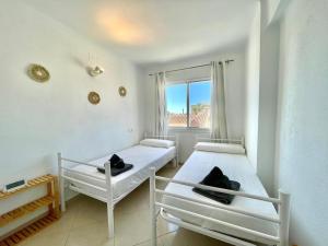two beds in a room with a window at Apartamento El Nido in Torre del Mar