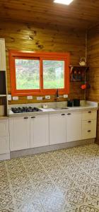 a kitchen with white cabinets and an orange window at Chalé Vale das Montanhas in Timbe do Sul