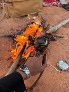 a person holding a pot over a fire at RUM PRESTIGE lUXURY CAMP & DESERT TOURS in Wadi Rum