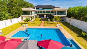 an aerial view of a house with a swimming pool with umbrellas at Madigane Residence Assinie in Assinie