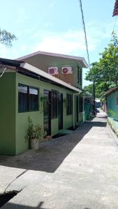 a green building with a sidewalk in front of it at Apartamentos Caimán Tortuguero in Tortuguero