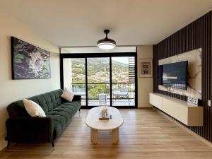 a living room with a green couch and a table at Panoramic view apartment with Pool and Rooftop in San Salvador