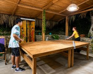 a man and a woman standing around a ping pong table at Entre Bosques Tayrona in Los Naranjos +65 photos