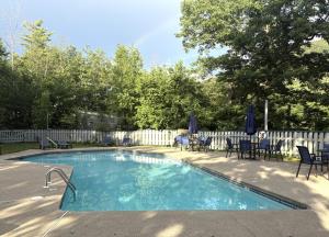 a swimming pool with chairs and umbrellas in a yard at Loon Resort Condo-AC, Pool, Hot Tub and Views in Lincoln