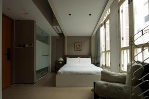 a bedroom with a bed and a chair and windows at Aura Hotel Purvis in Singapore +62 photos