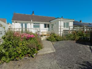 a white house with flowers in front of it at 7 Bro Branwen in Aberffraw