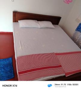 a bed with red and white sheets and pillows at QUEEN SASTINA guest house in Nilaveli