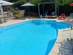 a blue swimming pool with chairs and an umbrella at Chalets avec Terrasse - Capacité 5 Pers. - FR-1-489-288 in Échassières