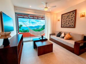 a living room with a couch and a large window at Mabay in Zihuatanejo